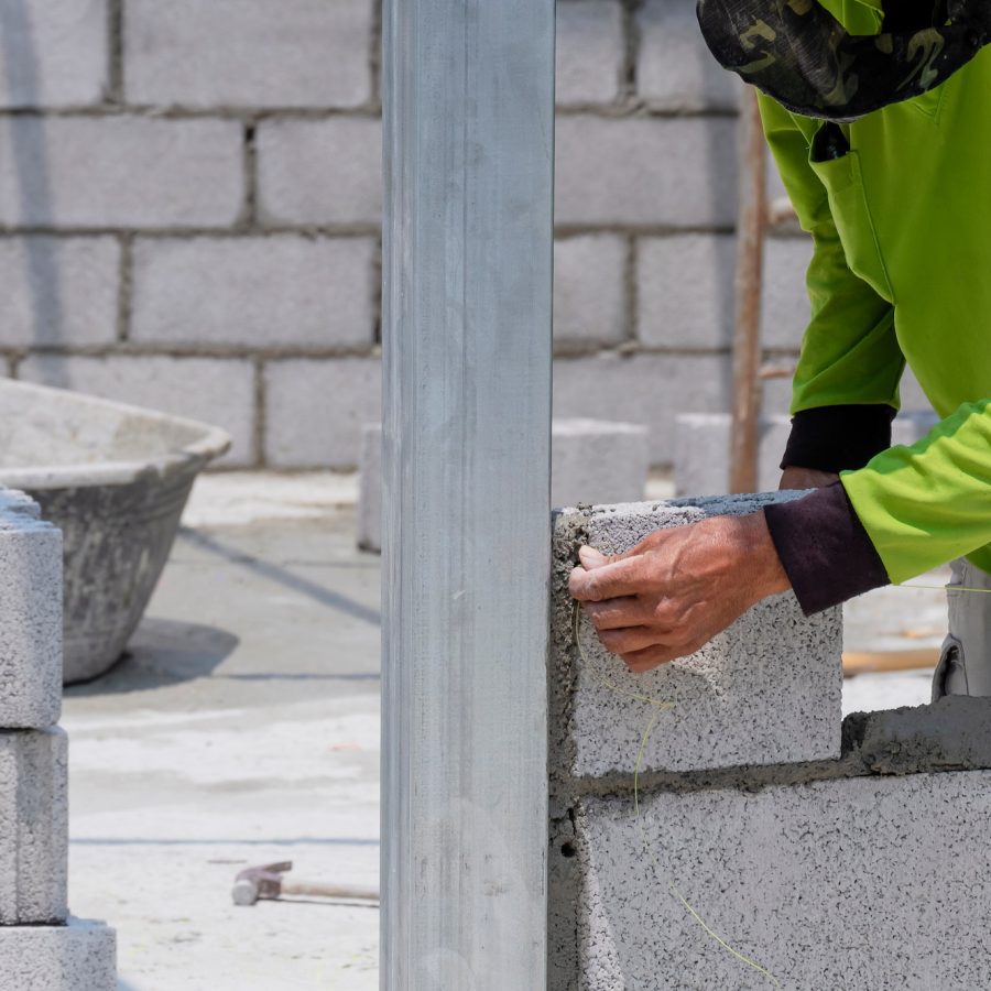 Builder worker hand setting nylon level line for building brick wall in house construction site