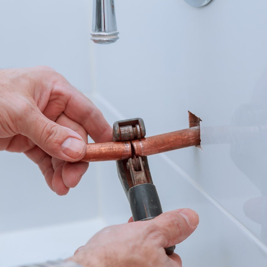 hand of working cutting copper pipe plumbing